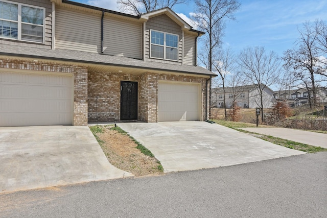 view of property with brick siding, a garage, and driveway