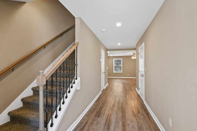hallway featuring recessed lighting, stairs, baseboards, and wood finished floors