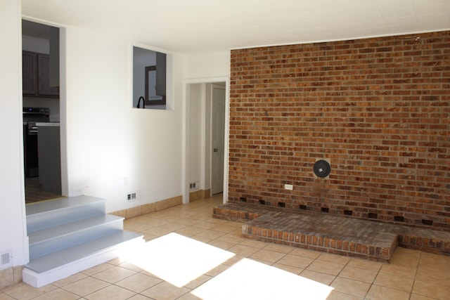 unfurnished living room featuring light tile patterned floors, visible vents, and brick wall