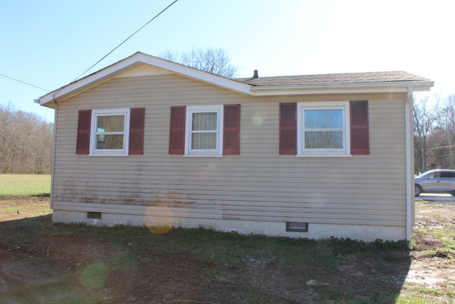 view of home's exterior with crawl space and a shingled roof