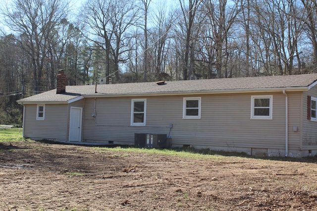 back of house featuring crawl space, cooling unit, and a chimney
