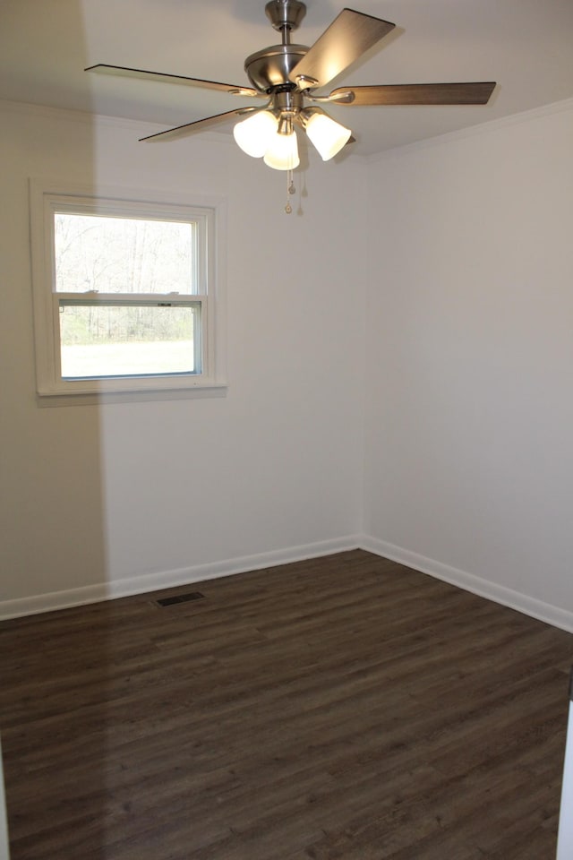 unfurnished room with visible vents, ornamental molding, a ceiling fan, dark wood finished floors, and baseboards