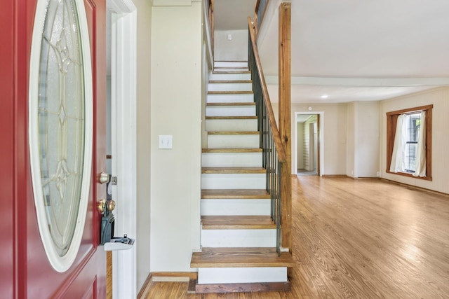foyer entrance featuring baseboards, wood finished floors, and stairs