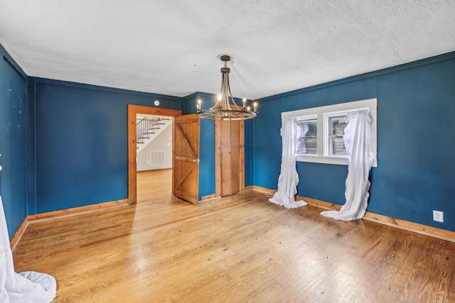 interior space featuring stairway, wood finished floors, an inviting chandelier, baseboards, and visible vents