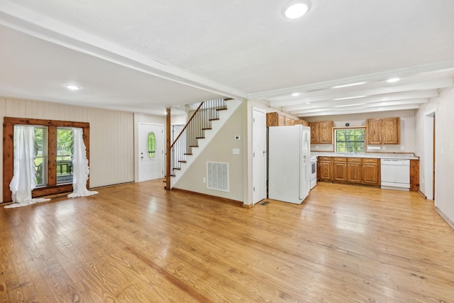 unfurnished living room with visible vents, recessed lighting, light wood-style floors, beamed ceiling, and stairs