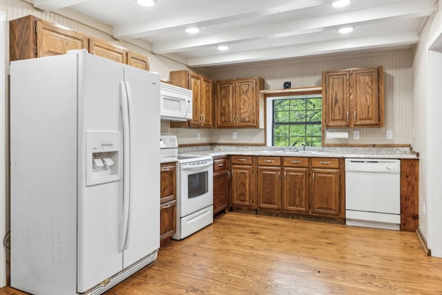 kitchen with brown cabinetry, light wood finished floors, beam ceiling, and white appliances