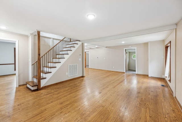 unfurnished living room with baseboards, light wood-style flooring, visible vents, and stairs
