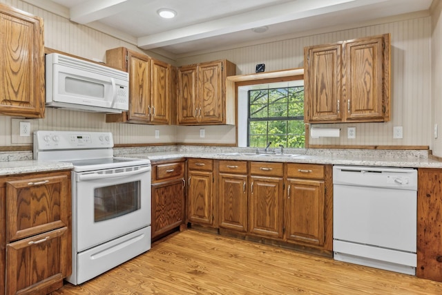 kitchen with light countertops, a sink, white appliances, light wood-type flooring, and brown cabinetry
