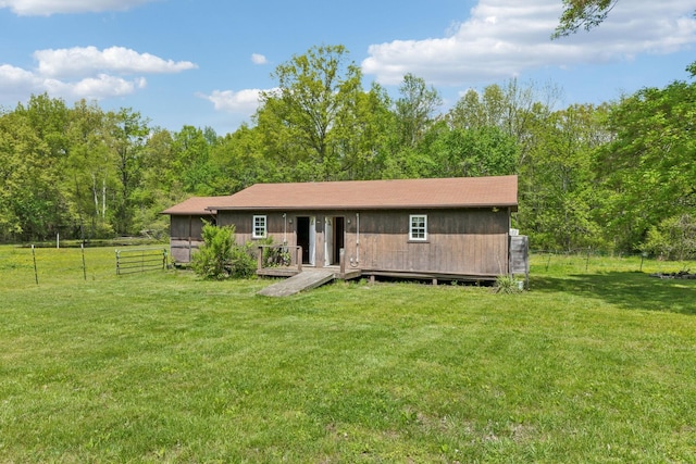 view of front of property with fence, a front lawn, and a wooded view
