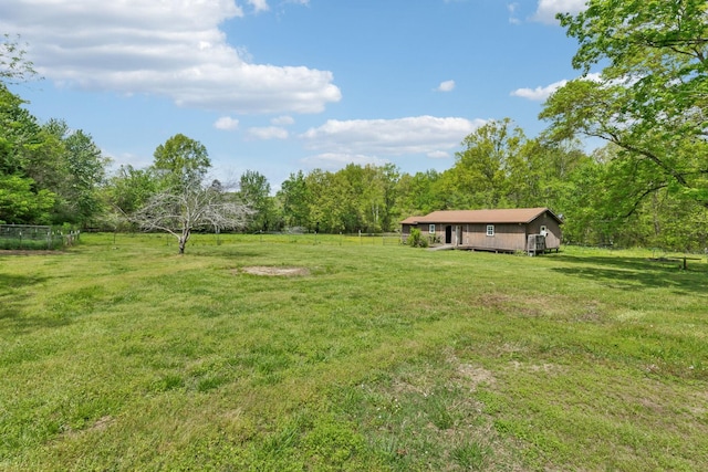 view of yard featuring a wooded view, fence, and a rural view