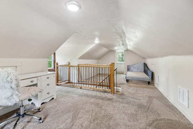 unfurnished office featuring light carpet, vaulted ceiling, visible vents, and baseboards