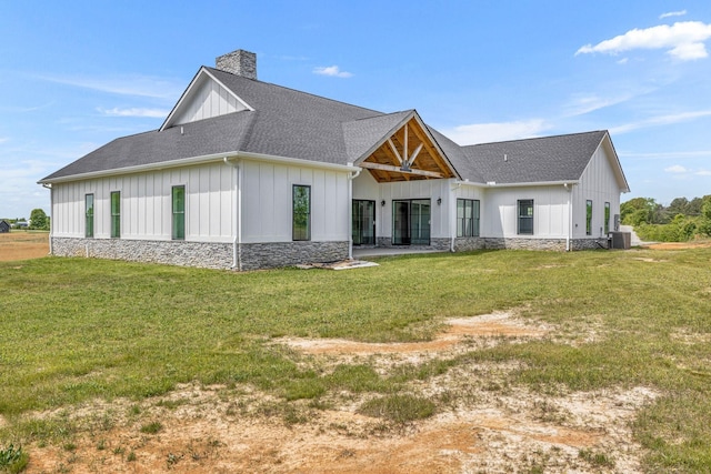 184 Emma Ln, Hohenwald, TN 38462 - rear view of house featuring stone siding, a yard, roof with shingles, board and batten siding, and a chimney