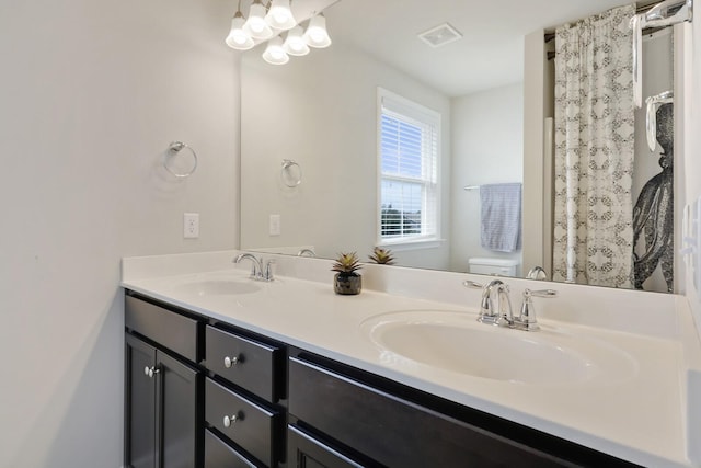 bathroom featuring a sink, visible vents, toilet, and double vanity