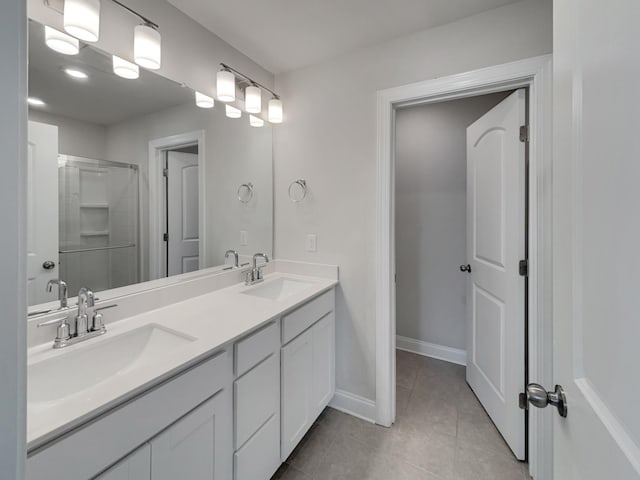 bathroom featuring tile patterned flooring, a shower stall, baseboards, and a sink
