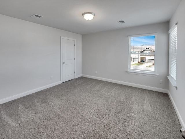 empty room featuring visible vents, baseboards, and carpet