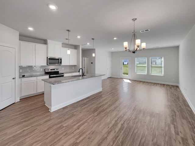 kitchen with a sink, white cabinets, light wood-style floors, appliances with stainless steel finishes, and tasteful backsplash