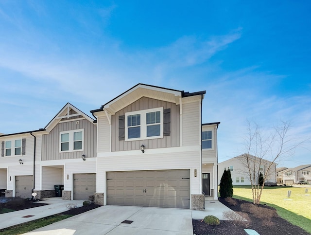 view of front of property featuring stone siding, board and batten siding, driveway, and a garage