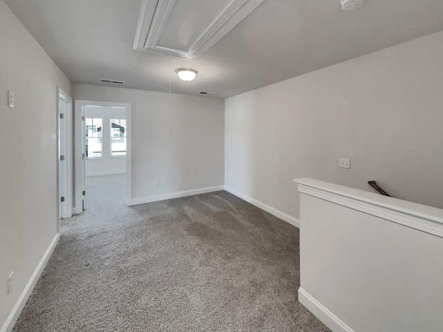 spare room featuring visible vents, baseboards, attic access, and carpet flooring