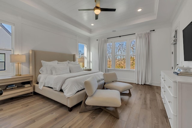 bedroom with recessed lighting, light wood-type flooring, crown molding, a tray ceiling, and a ceiling fan