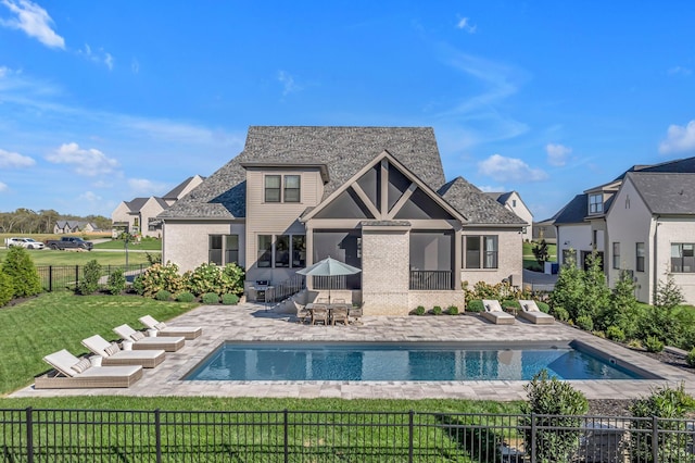 rear view of property featuring a patio, fence private yard, a fenced in pool, and a lawn