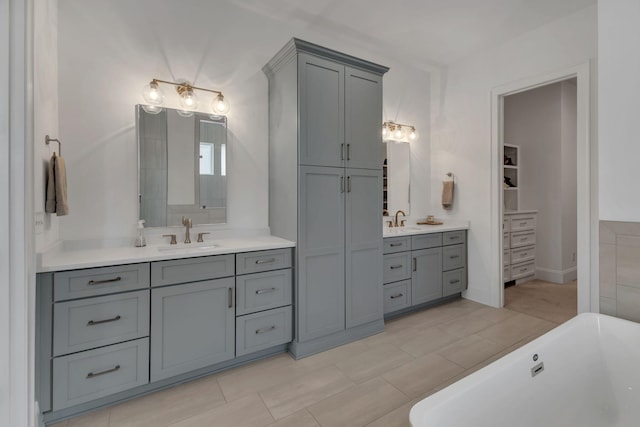 bathroom with two vanities, a sink, and a freestanding tub
