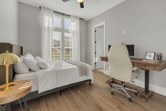 bedroom with ceiling fan, wood finished floors, and baseboards