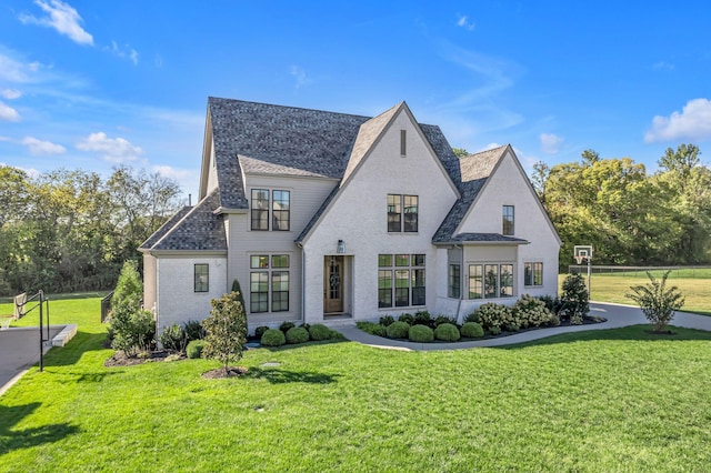 rear view of property featuring a shingled roof and a lawn