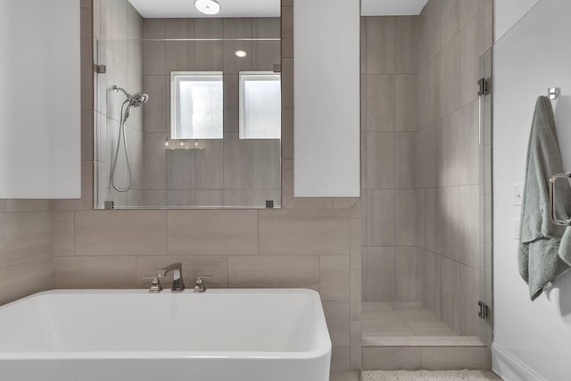 full bathroom with tile walls, a freestanding bath, a shower stall, and a sink