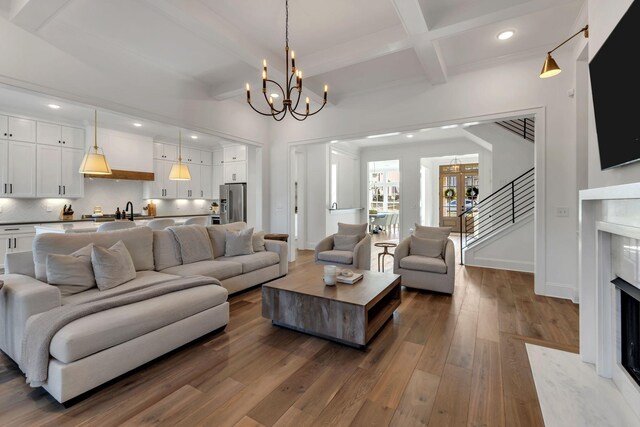 living area with wood-type flooring, beam ceiling, recessed lighting, a fireplace, and a notable chandelier