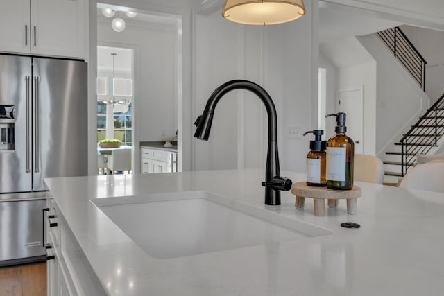 room details featuring a sink, white cabinets, high quality fridge, and light countertops