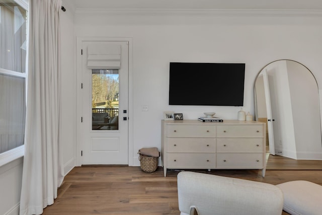 living area with baseboards, wood finished floors, and crown molding