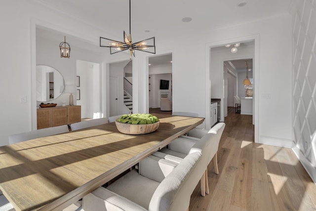 dining room featuring stairway, a notable chandelier, crown molding, and light wood finished floors