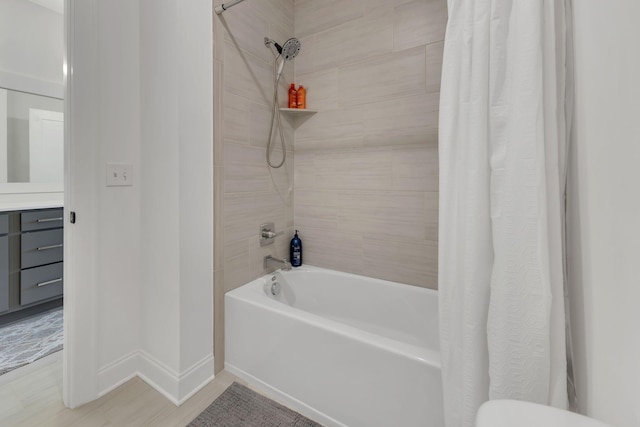 full bath with baseboards, shower / bathtub combination with curtain, wood finished floors, and vanity
