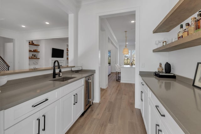 bar featuring beverage cooler, crown molding, light wood-style flooring, and a sink