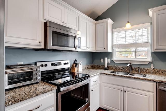 kitchen featuring vaulted ceiling, a toaster, white cabinetry, appliances with stainless steel finishes, and a sink