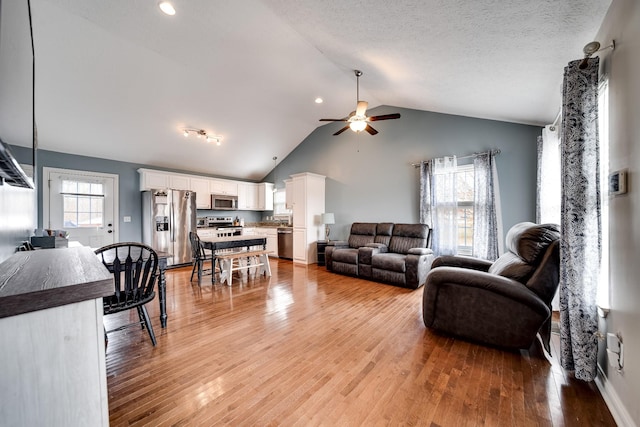 living area with light wood-style flooring, a ceiling fan, lofted ceiling, and recessed lighting