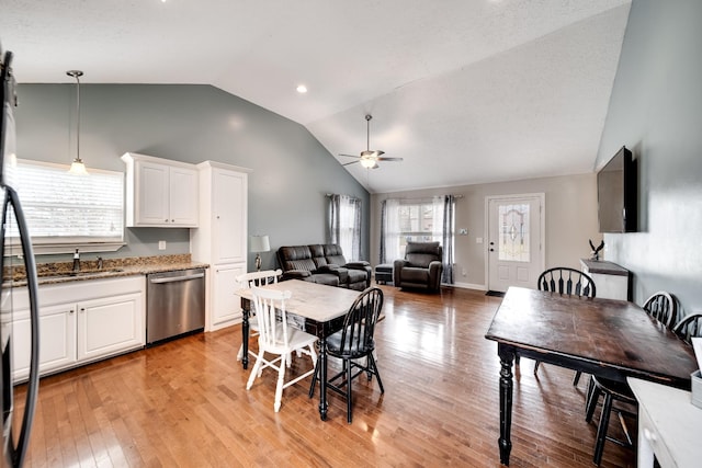 dining room featuring light wood-style flooring, high vaulted ceiling, a ceiling fan, and a wealth of natural light