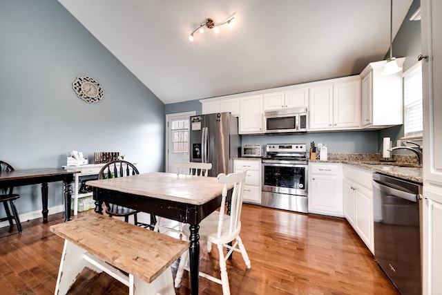 kitchen with white cabinets, vaulted ceiling, and stainless steel appliances