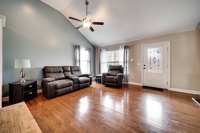 living area with wood finished floors, ceiling fan, baseboards, and high vaulted ceiling