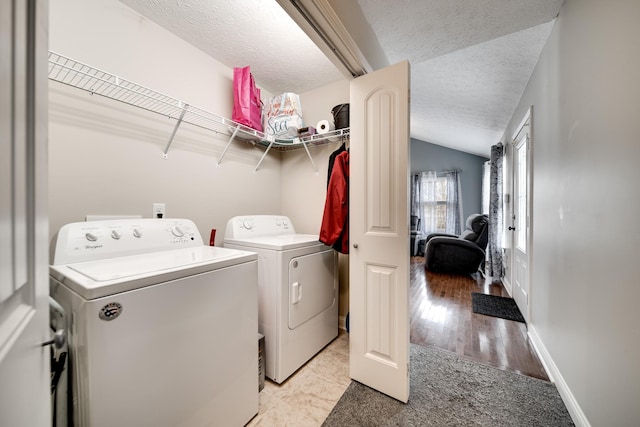 laundry area with laundry area, a textured ceiling, light carpet, baseboards, and washing machine and dryer