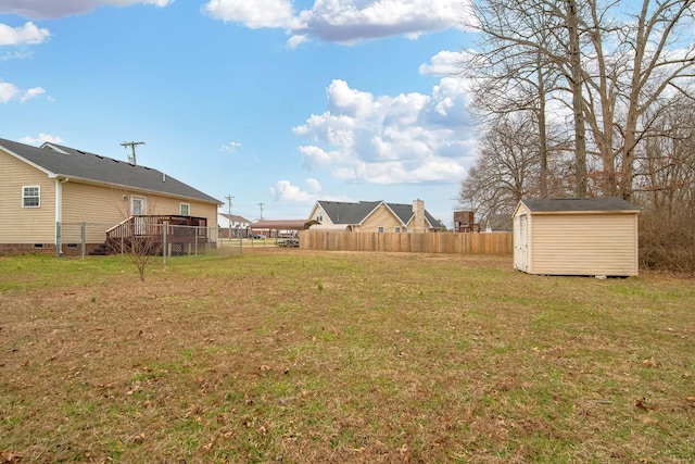 view of yard with fence, an outdoor structure, a deck, and a storage unit