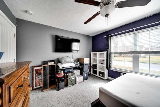 carpeted bedroom featuring ceiling fan and a textured ceiling