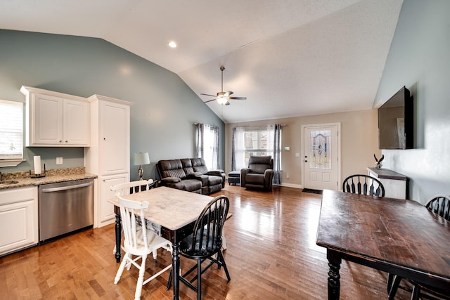 dining room with light wood-style flooring, high vaulted ceiling, a ceiling fan, and plenty of natural light