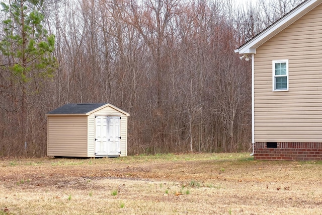 view of yard featuring a view of trees, an outbuilding, and a shed