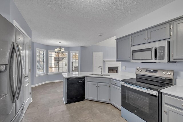 kitchen with gray cabinets, a peninsula, a notable chandelier, stainless steel appliances, and a sink