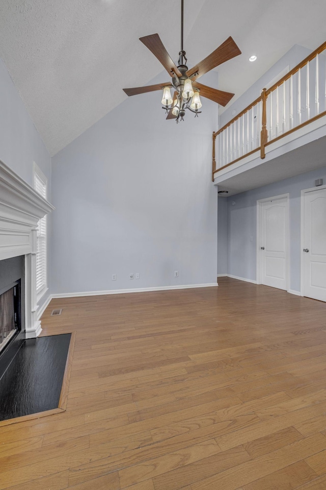 unfurnished living room featuring high vaulted ceiling, a ceiling fan, wood finished floors, a fireplace, and baseboards