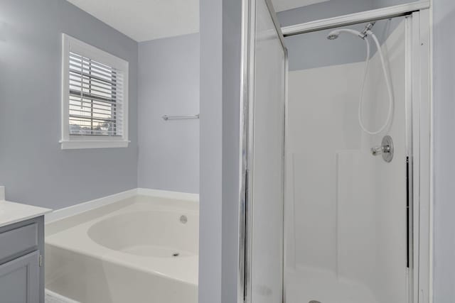 bathroom with a bath, a shower stall, a textured ceiling, and vanity