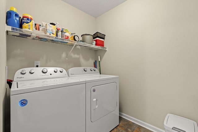 clothes washing area featuring laundry area, stone finish flooring, baseboards, and separate washer and dryer