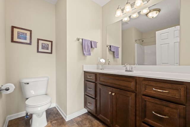 bathroom with vanity, toilet, a shower, and baseboards