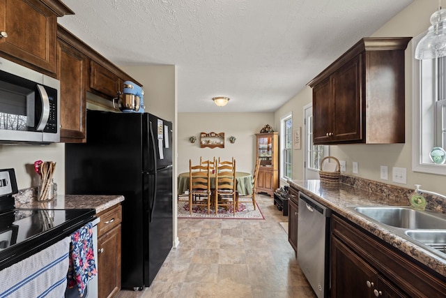 kitchen with dark brown cabinets, appliances with stainless steel finishes, a textured ceiling, and a sink